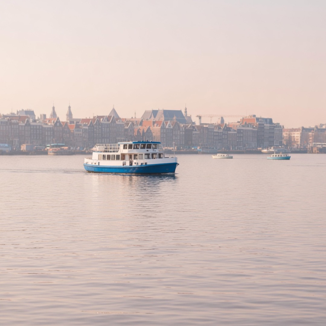 Blue and white ferry crossing the IJ with the Amsterdam skyline behind