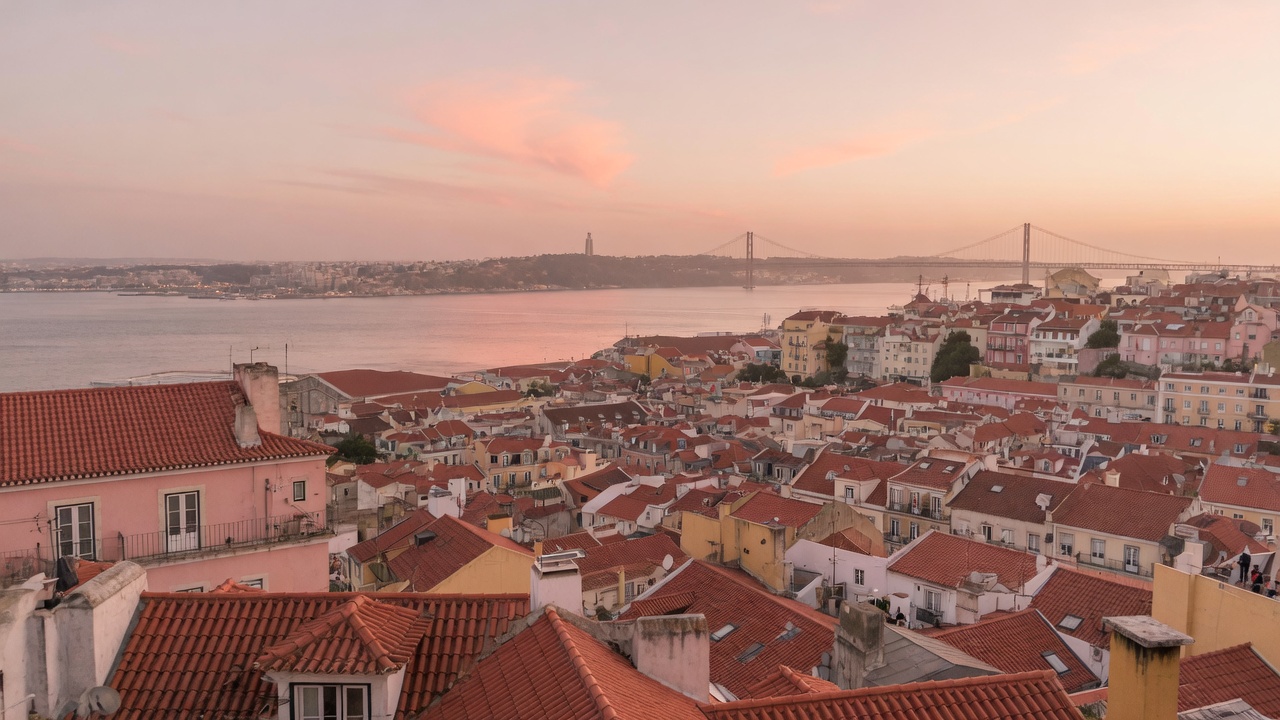 Lisbon dusk over rooftops toward the Tagus at golden hour