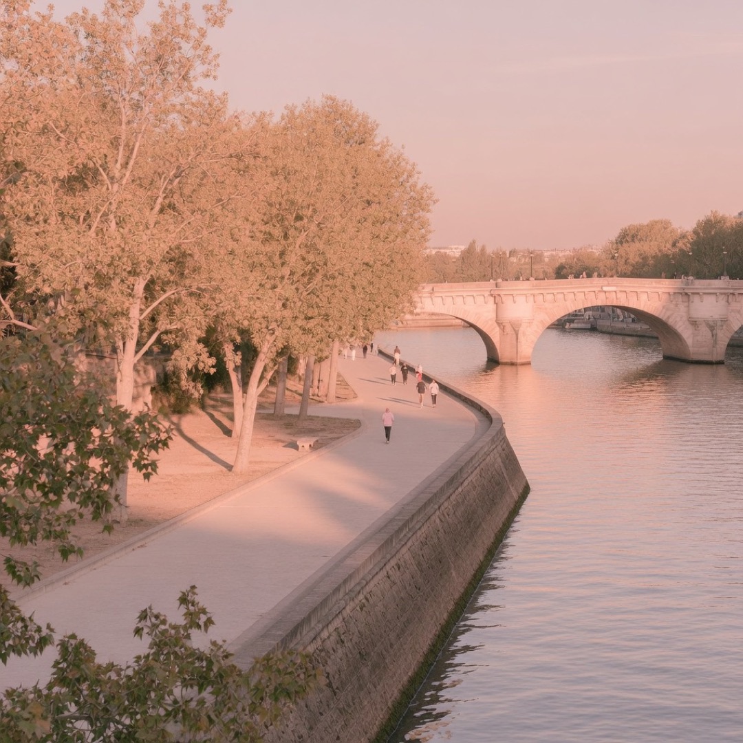 People walking along the Seine riverbanks in Paris at dusk
